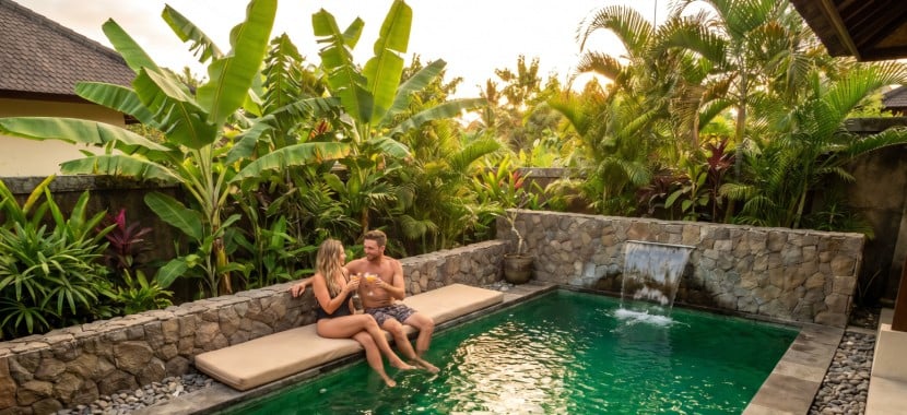 un couple se rafraichissant au bord d'une piscine ambiance bali