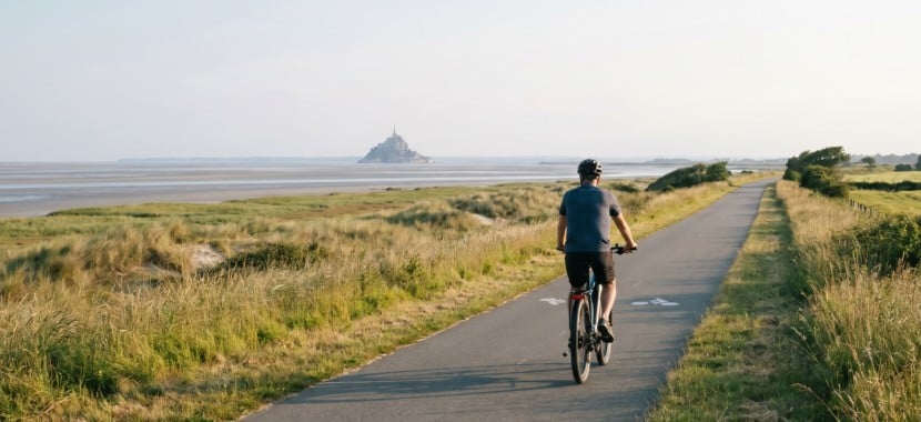 un cycliste sur une route vers le mont-saint-michel